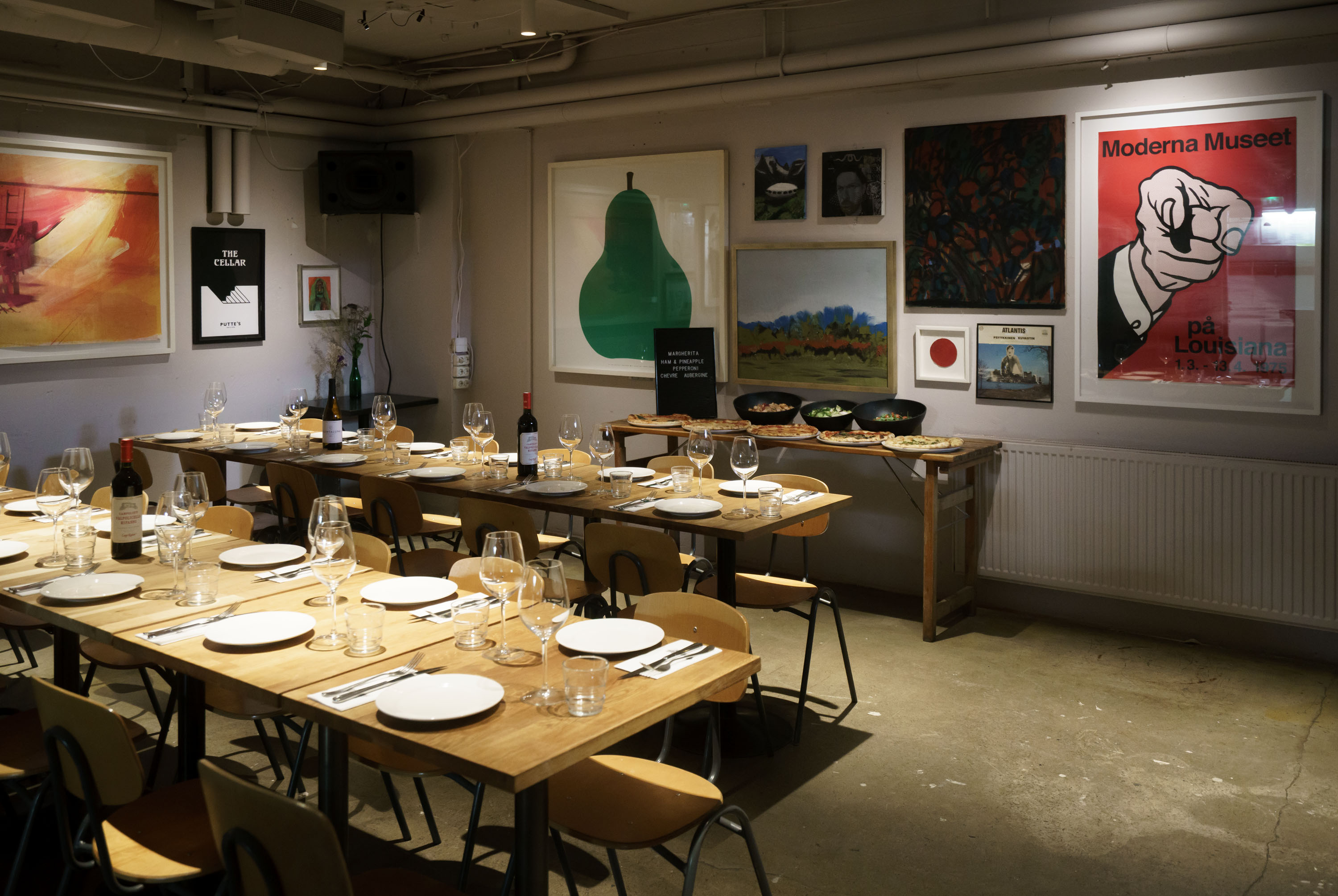 Set tables and a pizza buffet in front of the artwork